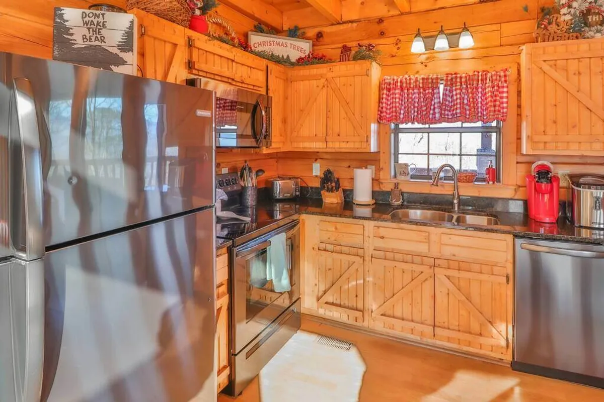 A warm, welcoming kitchen featuring stainless steel appliances, wooden cabinets, checkered curtains, and decorative signs. The scene suggests a lively, family-friendly environment perfect for cooking meals or baking treats during holidays.