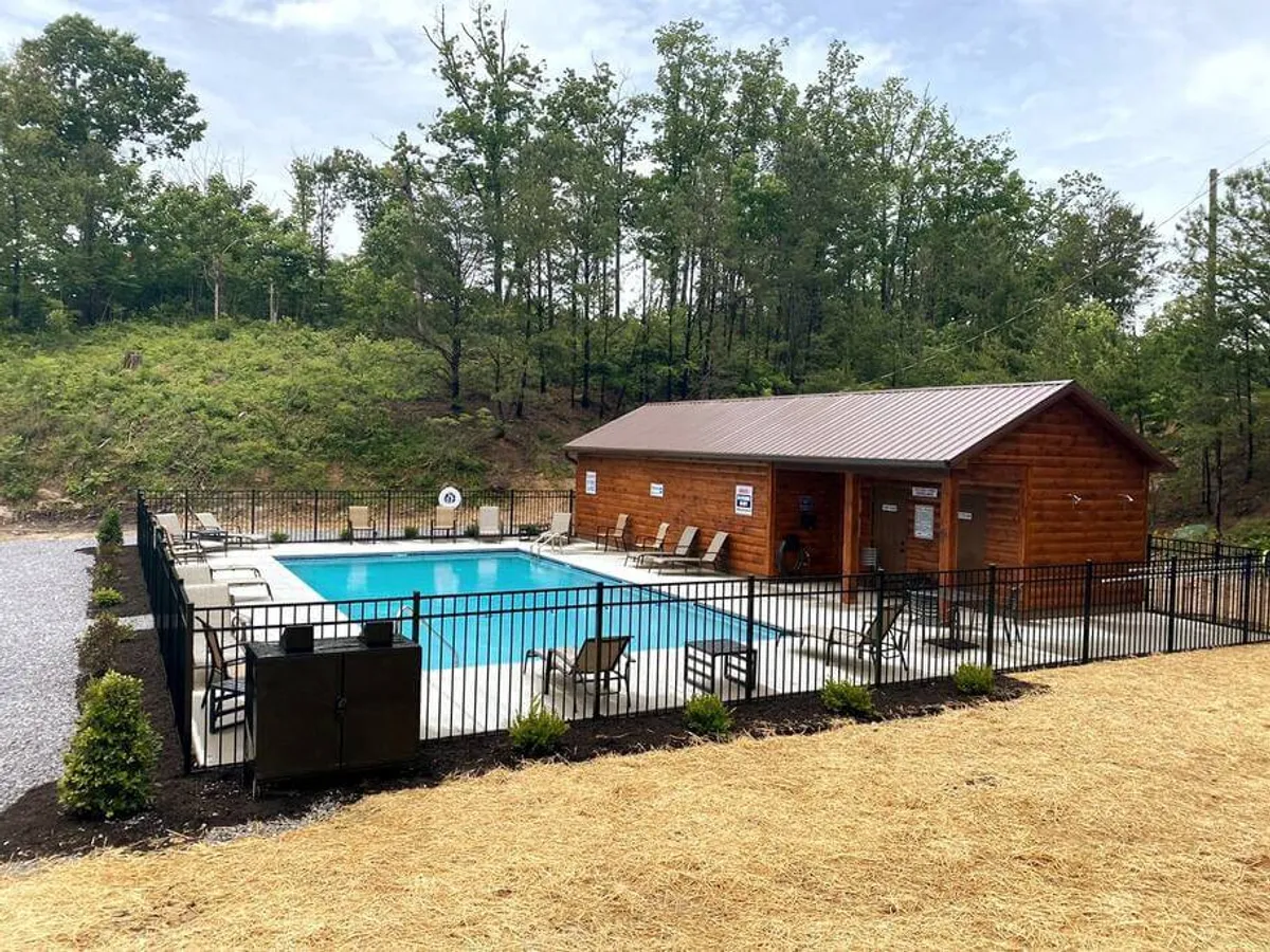 This image shows a sparkling swimming pool surrounded by lounge chairs and a clubhouse, enclosed within a fenced area. The atmosphere is inviting, with plenty of space for families to swim, sunbathe, and gather for social activities.