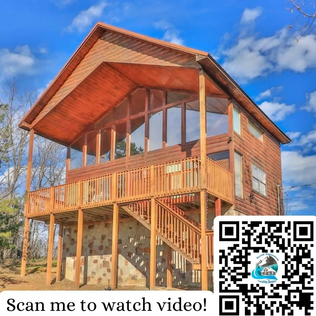 The image showcases the exterior of a charming mountain cabin in Sevierville, Tennessee, featuring large windows that invite natural light, a spacious wooden deck perfect for gatherings, and a sturdy stone foundation. The cabin is surrounded by serene mountain scenery, with the deck offering sweeping views ideal for admiring sunsets or enjoying morning coffee amidst nature.