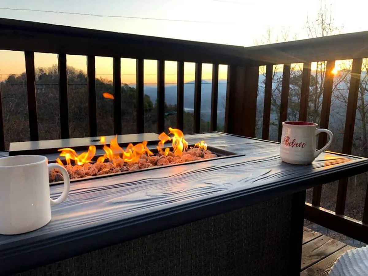 An exterior scene featuring a fire pit, coffee mugs, and a sunset view. The setting suggests evening relaxation and quality family time, with seating arranged for cozy conversations and memorable moments under the sky.